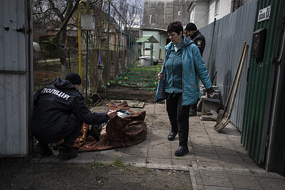 Policista prohlíží muže zabitého během války s Ruskem v Buči na předměstí...