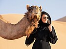 ena v emirátském národním odvu (abája) s velbloudem v poutních dunách Empty...