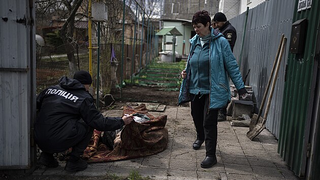 Policista prohlíží muže zabitého během války s Ruskem v Buči na předměstí Kyjeva. (11. dubna 2022)