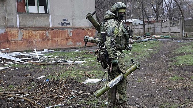 Ozbrojený voják milice samozvané Doněcké republiky prochází kolem budovy v Mariupolu.(13. dubna 2022)