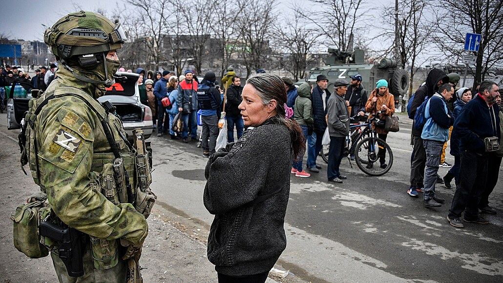 ena mluví s ruským vojákem v Mariupolu, zatímco lidé ekají ve front na...
