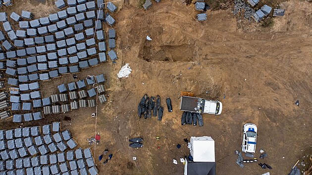 Francouzští a ukrajinští forenzní experti vyzvedávají těla obětí ruské agrese z masových hrobů ve městě Buča. (16. dubna 2022)