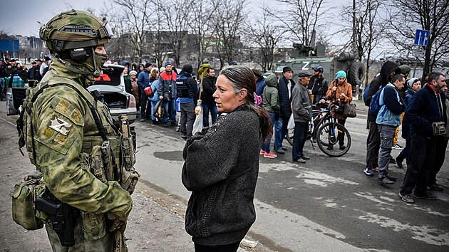 ena mluví s ruským vojákem v Mariupolu, zatímco lidé ekají ve front na...