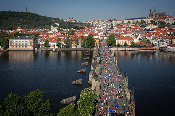 Závodníci na Karlov most s Praským hradem a Petínem v pozadí. Praský...