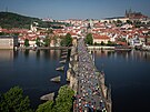 Závodníci na Karlov most s Praským hradem a Petínem v pozadí. Praský...