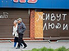 Obyvatele Mariupolu prochází kolem budovy s nápisem "Tady ijí lidé". (5....