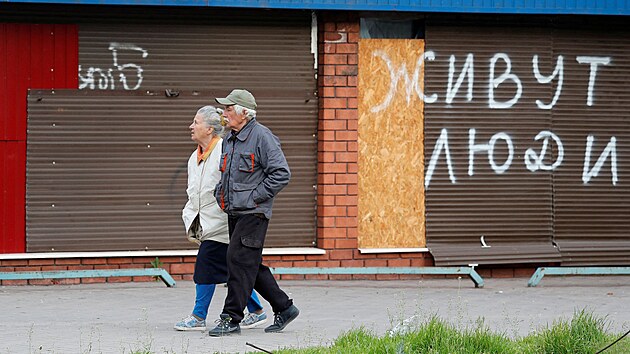 Obyvatele Mariupolu prochází kolem budovy s nápisem "Tady ijí lidé". (5....
