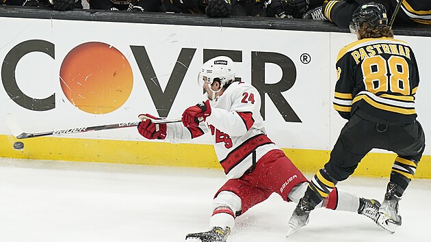 Seth Jarvis (24) z Carolina Hurricanes pad v zpase s Boston Bruins, atakuje ho David Pastrk (88).