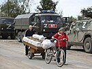 Místní obyvatelé procházejí kolem ruských vojenských vozidel v Mariupolu, na...