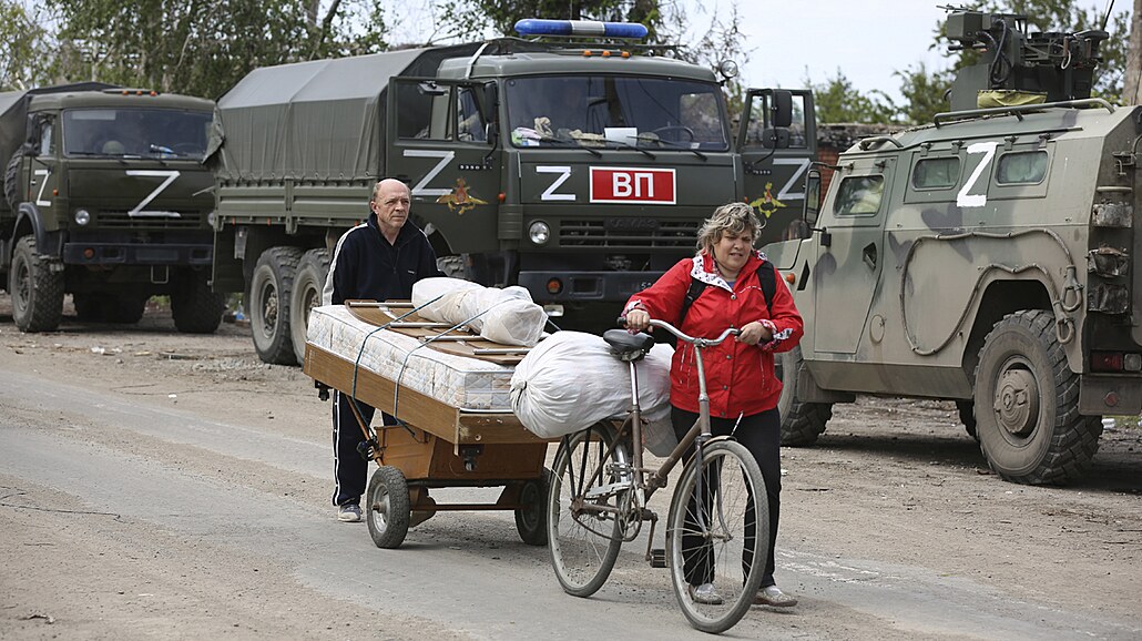 Místní obyvatelé procházejí kolem ruských vojenských vozidel v Mariupolu, na...