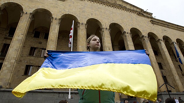 Demonstrantka drží ukrajinskou státní vlajku během protestu proti ruské invazi na Ukrajinu v Tbilisi. (8. května 2022)