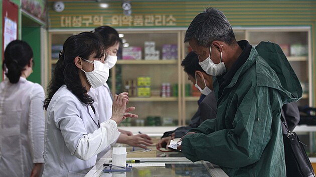 Zaměstnanci lékárny v Pchjongjangu prodávají léky zatímco se zemí šíří covid-19. (15. května 2022)
