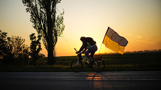 Mu na kole s ukrajinskou vlajkou jede na silnici mezi Odsou a Mykolajivem na jihu Ukrajiny. (14. kvtna 2022)
