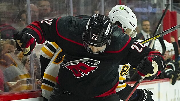 Brett Pesce (22) z Carolina Hurricanes a David Pastrk z Boston Bruins bojuj u mantinelu.