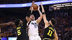 TSNÁ OBRANA. Luka Doni z Dallasu mezi dvojicí Kevon Looney a Klay Thompson z...