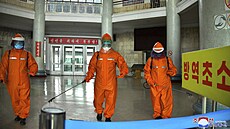 Pracovníci dezinfikují podlahu stanice metra v Pchjongjangu. (17. května 2022)