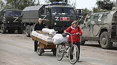 Místní obyvatelé procházejí kolem ruských vojenských vozidel v Mariupolu, na... | na serveru Lidovky.cz | aktuální zprávy