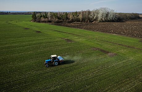 Traktor rozmetá hnojivo na poli poblí ukrajinské vesnice Jakovlivka.