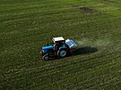 Traktor rozmetá hnojivo na poli poblí ukrajinské vesnice Jakovlivka.