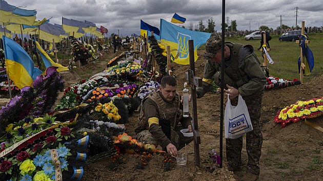 Ukrajinští vojáci navštěvují hrob zesnulého kamaráda na hřbitově v Charkově. (22. května 2022)