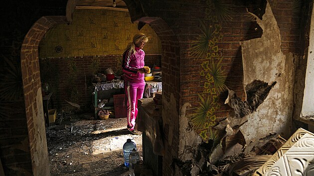 Žena hledá nepoškozené věci ve svém domě ve vesnici Velyka Kostromka zničeném po ruském bombardování. (19. května 2022)