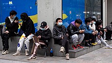 Mladí lidé odpočívají na ulici v čínském městě Wu-chan. (12. března 2021)