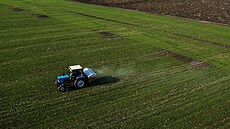 Traktor rozmetá hnojivo na poli poblí ukrajinské vesnice Jakovlivka.