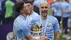 Pep Guardiola (vpravo), trenér Manchesteru City, se usmívá po zisku...