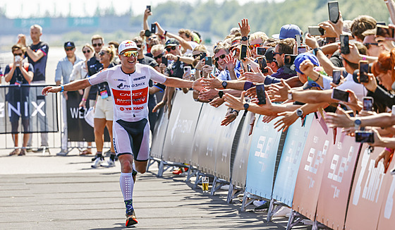 Norský závodník Kristian Blummenfelt se raduje s fanouky v cíli triatlonového...