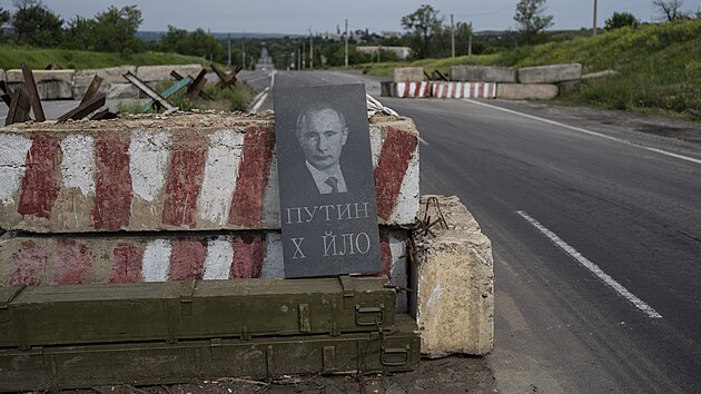 Na kontrolním stanovišti v Doněcké oblasti na východní Ukrajině je vidět vyobrazení ruského prezidenta Vladimira Putina a hanlivým vzkazem. (5. června 2022)