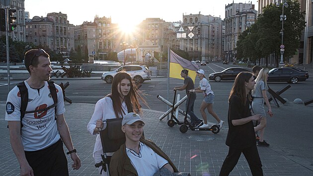 Lidé chodí po ulici při západu slunce na náměstí Nezávislosti v centru Kyjeva na Ukrajině. (8. června 2022)