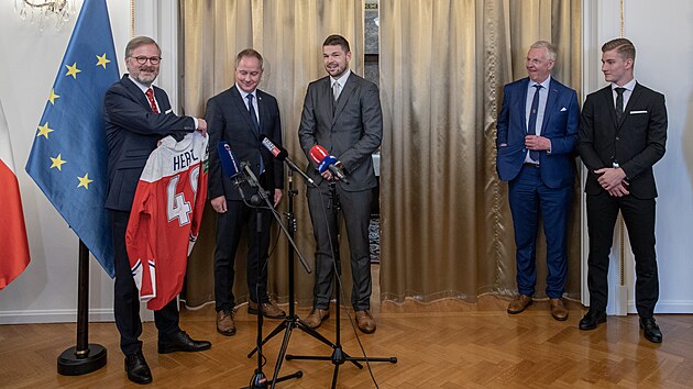 Pedseda vldy Petr Fiala pzuje s hokejovm dresem, emu pihl (zleva) ministr kolstv Petr Gazdk, tonk Tom Hertl, trenr Kari Jalonen a brank Luk Dostl.