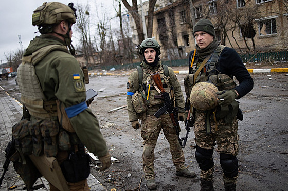 Ukrajinští vojáci prochází bojem zdevastovaným městem Irpiň. (2. dubna 2022)