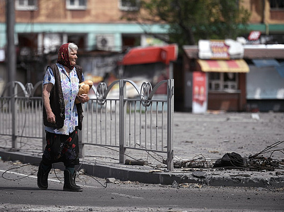Obyvatelka Mariupolu jde po ulici s nafasovanými bochníky chleba. (6. ervna...
