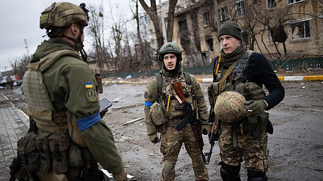 Ukrajintí vojáci prochází bojem zdevastovaným mstem Irpi. (2. dubna 2022)