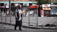 Obyvatelka Mariupolu jde po ulici s nafasovanými bochníky chleba. (6. �ervna...