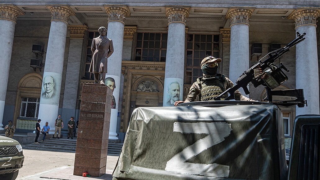 Ruský voják hlídkuje u budovy filhamonie v ukrajinském Mariupolu. (12. června...