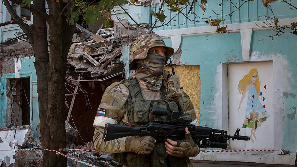 Ruský voják hlídkuje u zničené školy v ukrajinském Mariupolu. (13. června 2022)