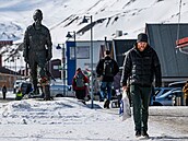 Lidé procházejí kolem sochy horníka na Špicberkách.