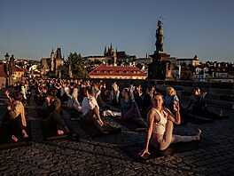 Několik stovek lidí si přišlo v den slunovratu za východu slunce zacvičit jógu...