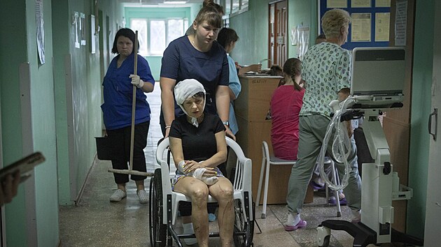Nemocniční sestra tlačí invalidní vozík s ženou zraněnou při ruském raketovém útoku na nákupní centrum v Kremenčuku. (28. června 2022)