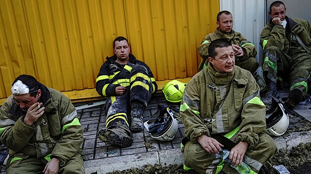 Hasiči odpočívají po práci v nákupním centru v Kremenčuku, které zasáhla ruská raketa. (28. června 2022)