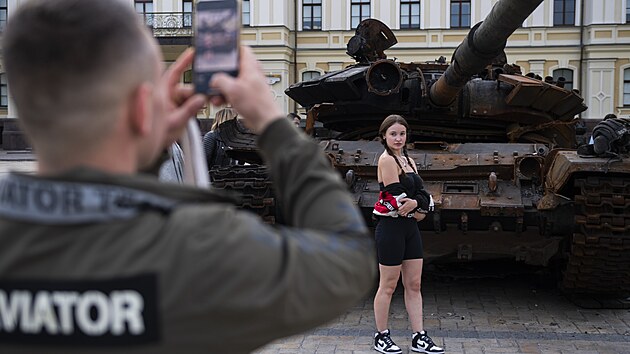 Mlad Ukrajinci se fot u znienho ruskho tanku v centru Kyjeva. (27. kvtna 2022)