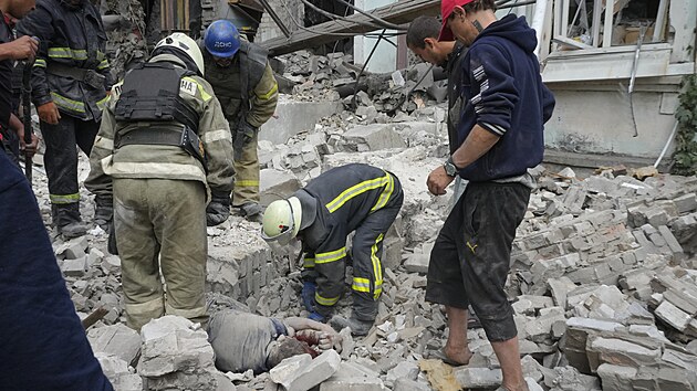 Záchranáři a místní obyvatelé vynášejí mrtvé tělo zpod trosek budovy po ruském náletu v Lysyčansku v Luhanské oblasti. (16. června 2022)