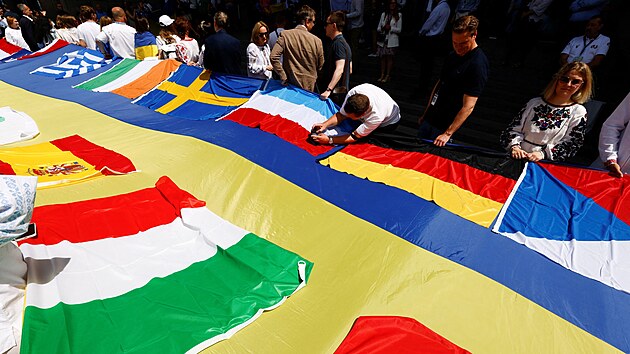 Evropt zkonodrci a ukrajint zstupci roztahuj ukrajinskou vlajku ped Evropskm parlamentem v den, kdy ldi projednvaj udlen statusu kandidtsk zem Ukrajin. (23. ervna 2022)