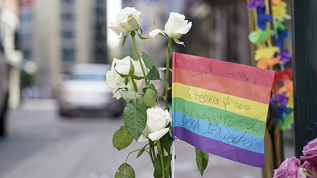 Květiny a duhová vlajka na chodníku jako uctění památky obětí střelby v London Pubu, oblíbeném gay baru a nočním klubu, v centru Osla (25. června 2022.)