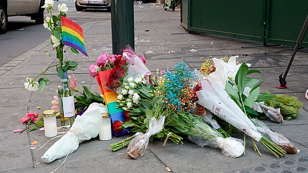 Květiny a duhová vlajka na chodníku jako uctění památky obětí střelby v London Pubu, oblíbeném gay baru a nočním klubu, v centru Osla (25. června 2022.)