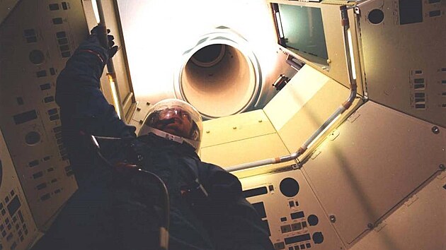 Odlehčená maketa kabiny posádky MOL s členem posádky v obleku s pohledem na úzký tunel vedoucí do kabiny Gemini-B.