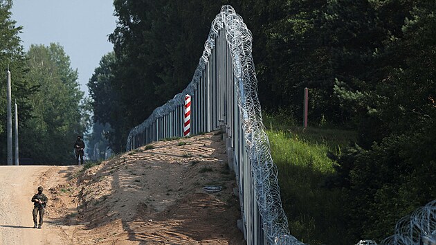Polští pohraničníci procházejí podél nového plotu na hranicích s Běloruskem. (30. června 2022)