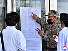 Severokorejský voják v Pchjongjangu vysvtluje epidemická pravidla. KLDR se...